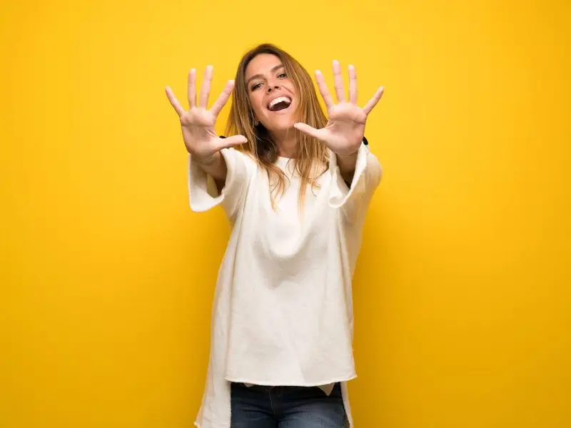 10 Free and Low Cost Online Tools for Small Business image shows a vibrant yellow background with a casually dressed lady holding up all 10 fingers