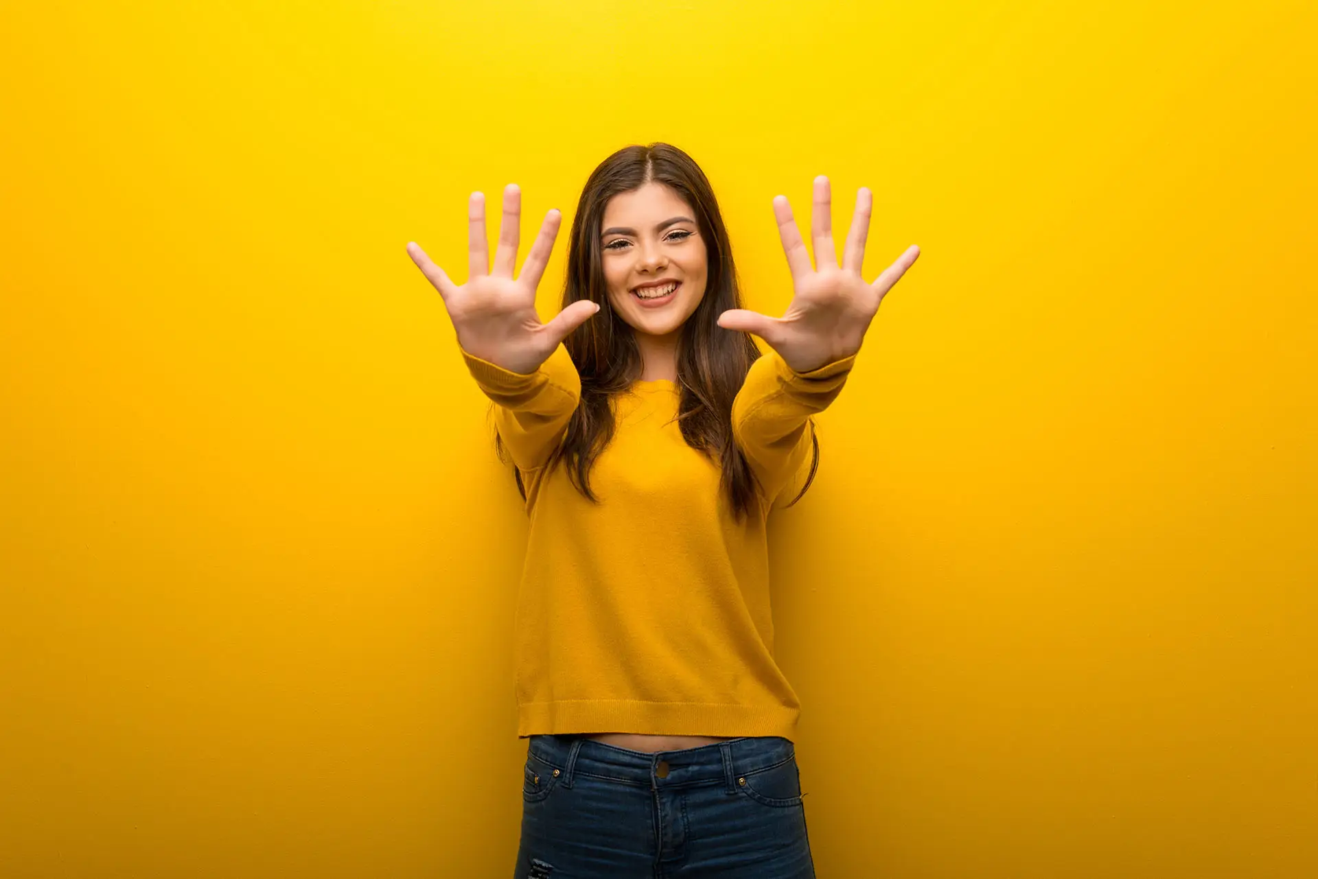 10 of Our Favourite WordPress Plugins picture shows a lady in a bright yellow jumper holding up all 10 fingers - concept for top ten favourite WordPress plugins