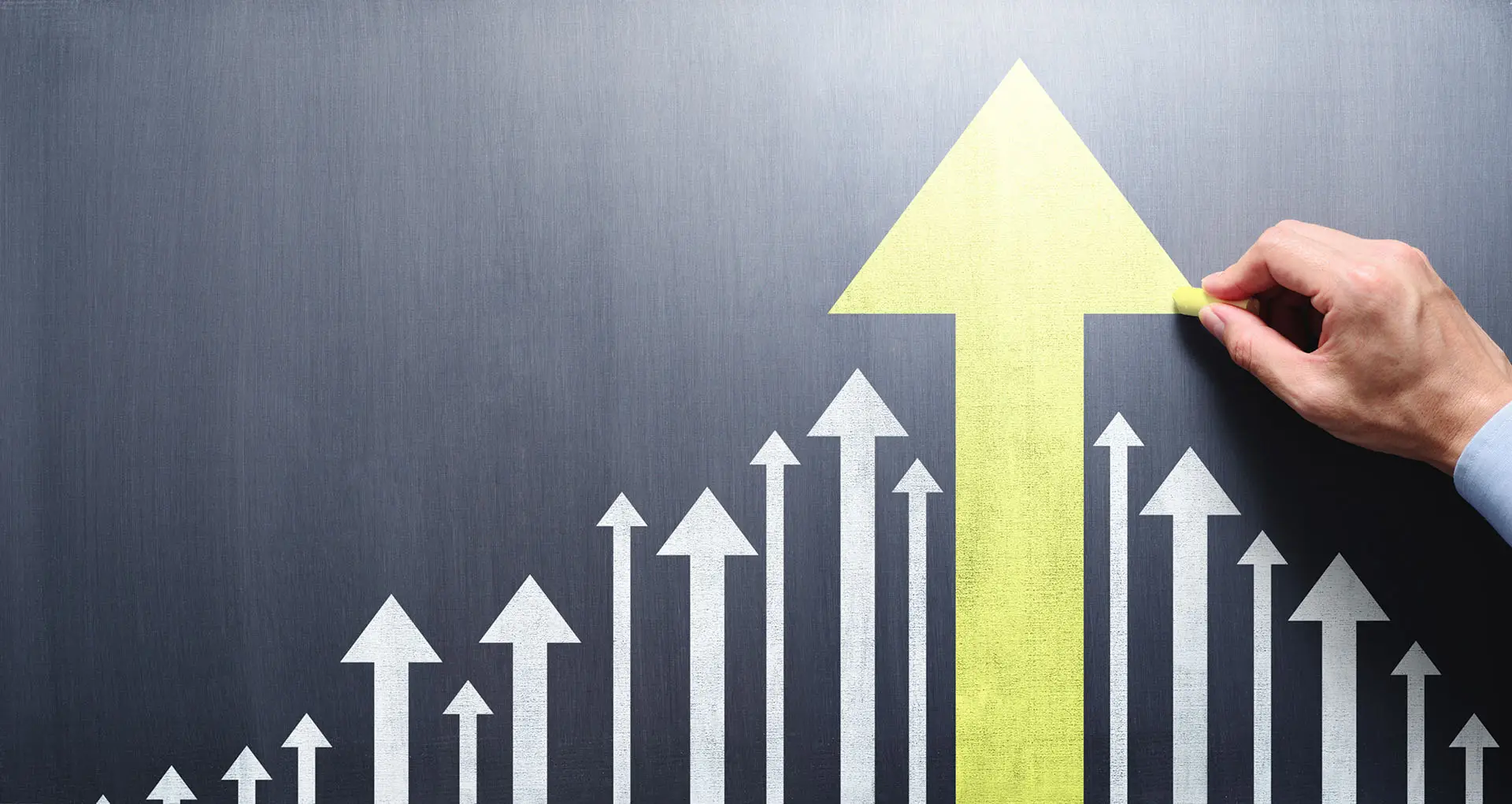 Business Development versus Personal Development this image shows a black board with various ascending arrows a hand is drawing the largest yellow arrow - concept for both business and personal development