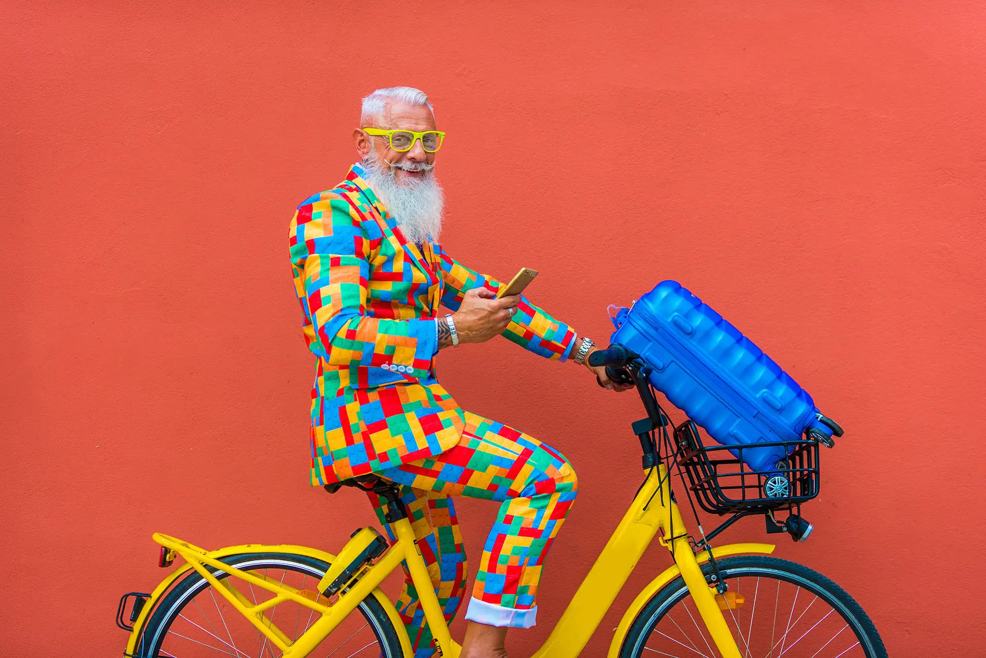 Don't Be a Copy, Be Original, this image shows a gentleman on a bright yellow bicycle, he is wearing a loud and vibrant multi coloured suit - concept for being original