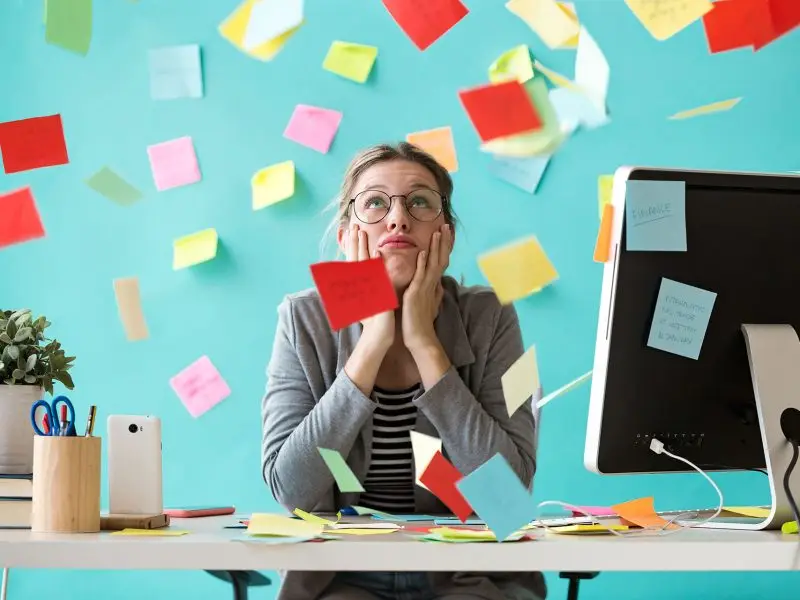 Goal Setting - the image shows a lady sat at her desk with post it notes raining down on her - concept for goal setting