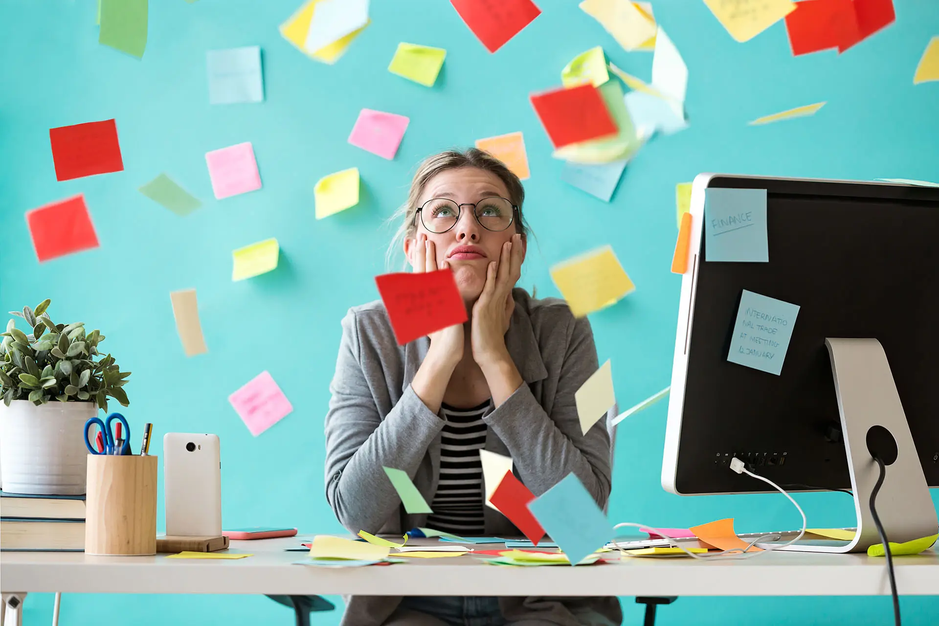 Goal Setting - the image shows a lady sat at her desk with post it notes raining down on her - concept for goal setting