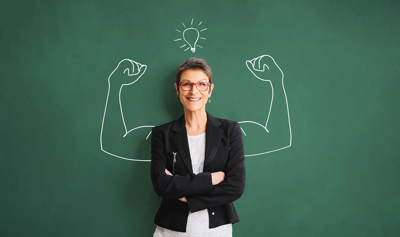 If You Don’t Believe in Yourself... images shows a middle aged lady leaning cross armed against a wall which has a chalk drawing of muscular arms - self belief concept