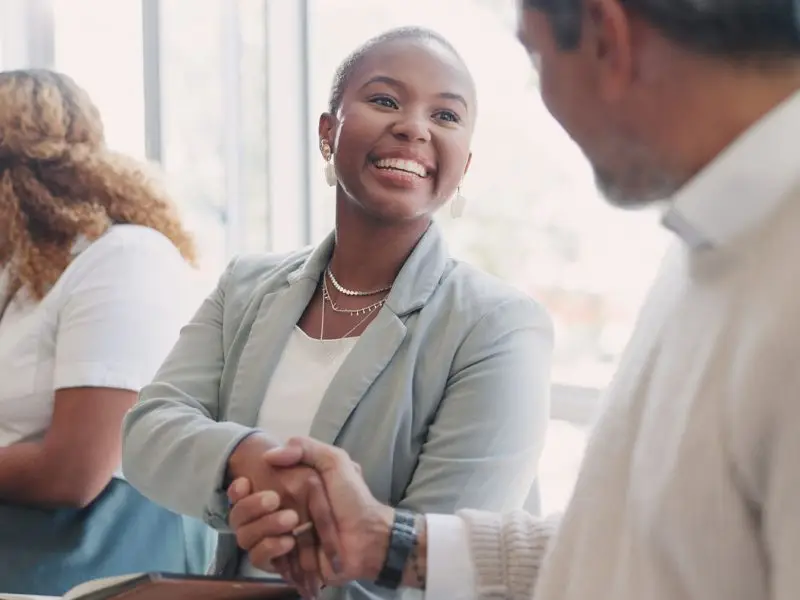 Making the Most of Your Networking Activities - this image shows business people meeting at a networking event, they are smiling and shaking hands