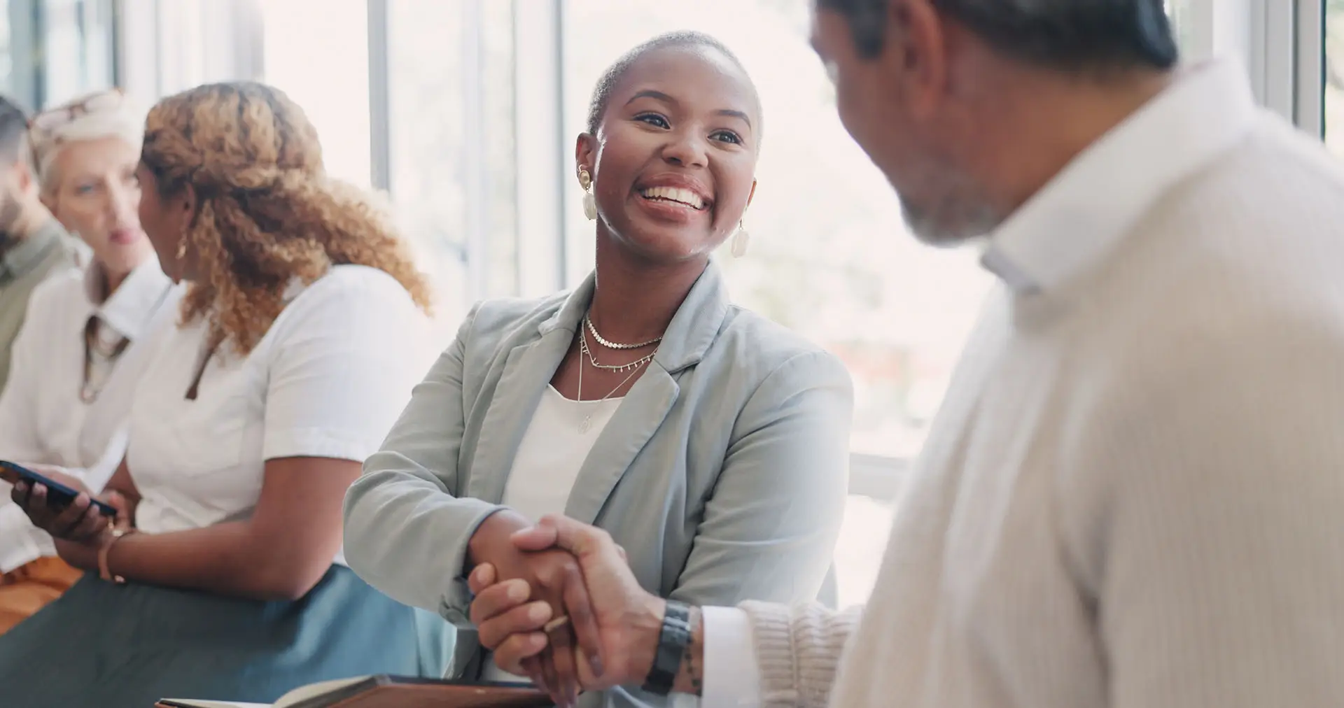 Making the Most of Your Networking Activities - this image shows business people meeting at a networking event, they are smiling and shaking hands