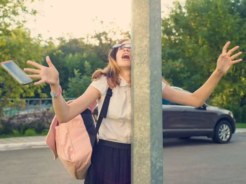 Managing Social Media Distractions image shows a young lady distracted by her mobile phone and has walked into a post making the phone fly out of her hand - social media distraction concept