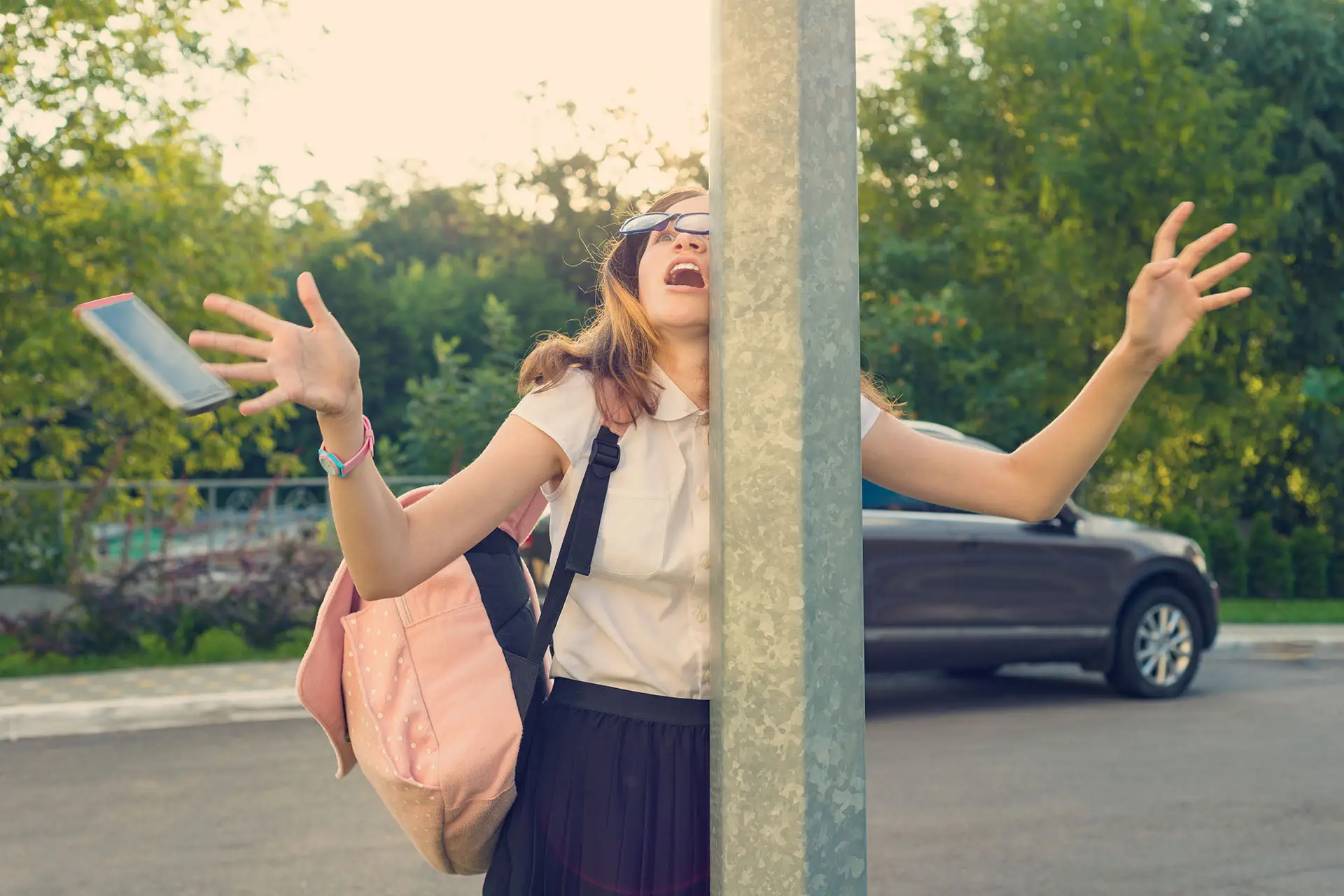 Managing Social Media Distractions image shows a young lady distracted by her mobile phone and has walked into a post making the phone fly out of her hand - social media distraction concept