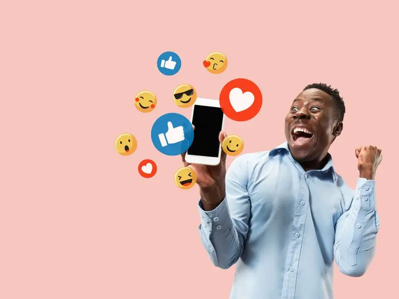 Paying for Facebook Adverts the image shows an excited young man holding a mobile phone with various Facebook icons coming out of it