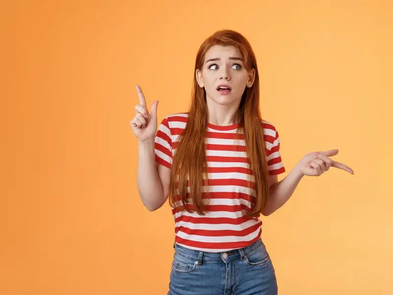 Positive Language, Positive Thought Process, Positive Outcome! Image shows a red head girl in a red strpy top who has one arm bent at the elbow with a finger pointing up and the other bent at the elbow pointing to the side as she weighs up the choice - positive mindset concept