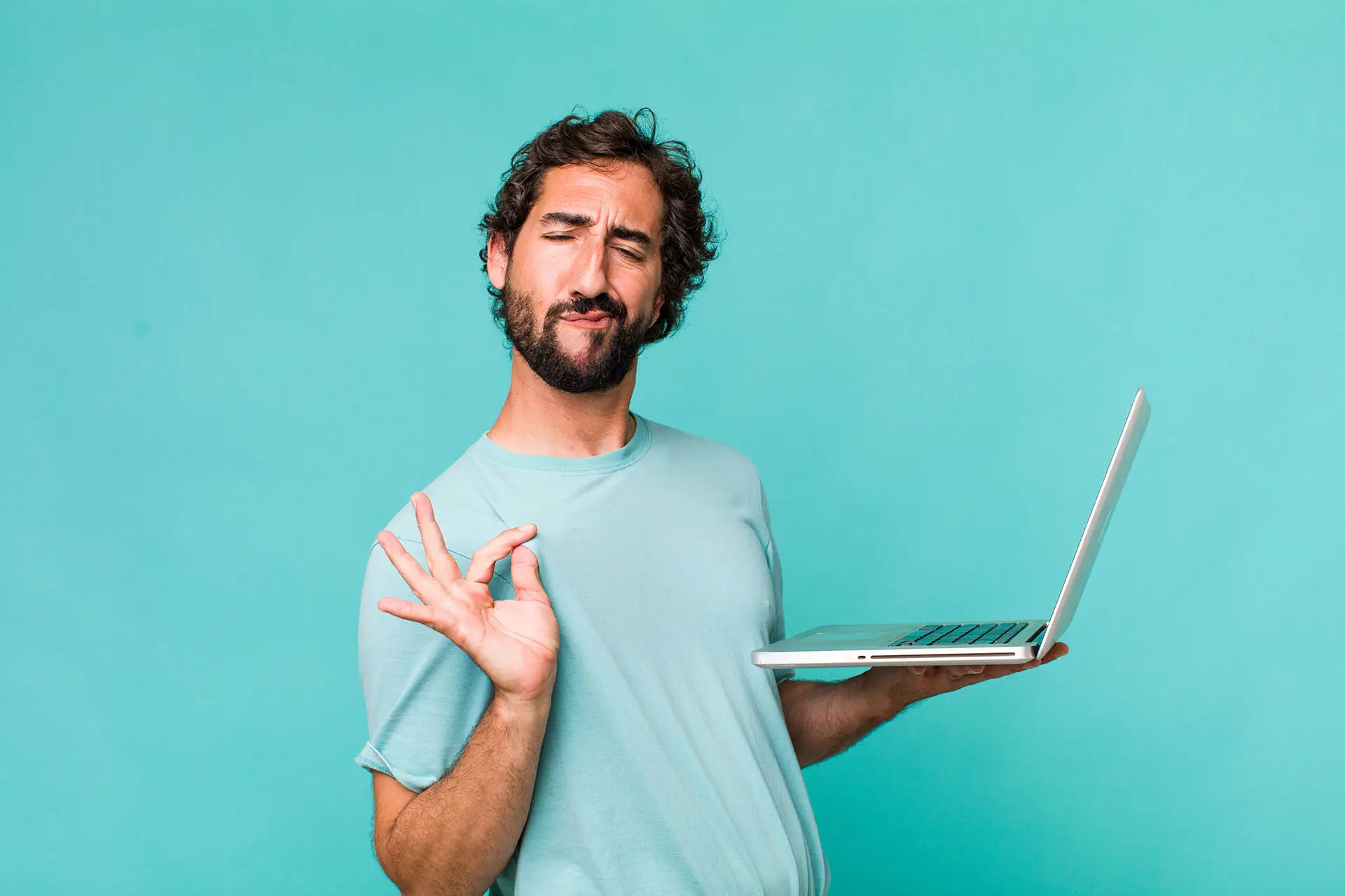 Put Some Personality into Your Blog Posts. This image is a bright blue background with an interesting looking man holding a laptop, looking opleased with himself and making a gesture that chefs would use when they have created a rather tasty dish - concept for Put Some Personality into Your Blog Posts