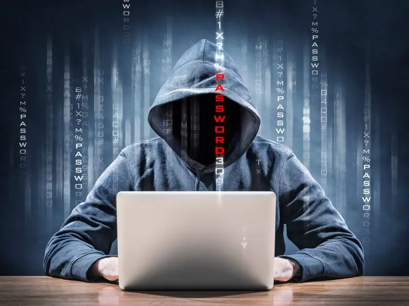 Security Tips for WordPress Websites this image shows a hooded figure sat at a laptop with code descending in lines with the middle line highlighted in red - website security concept