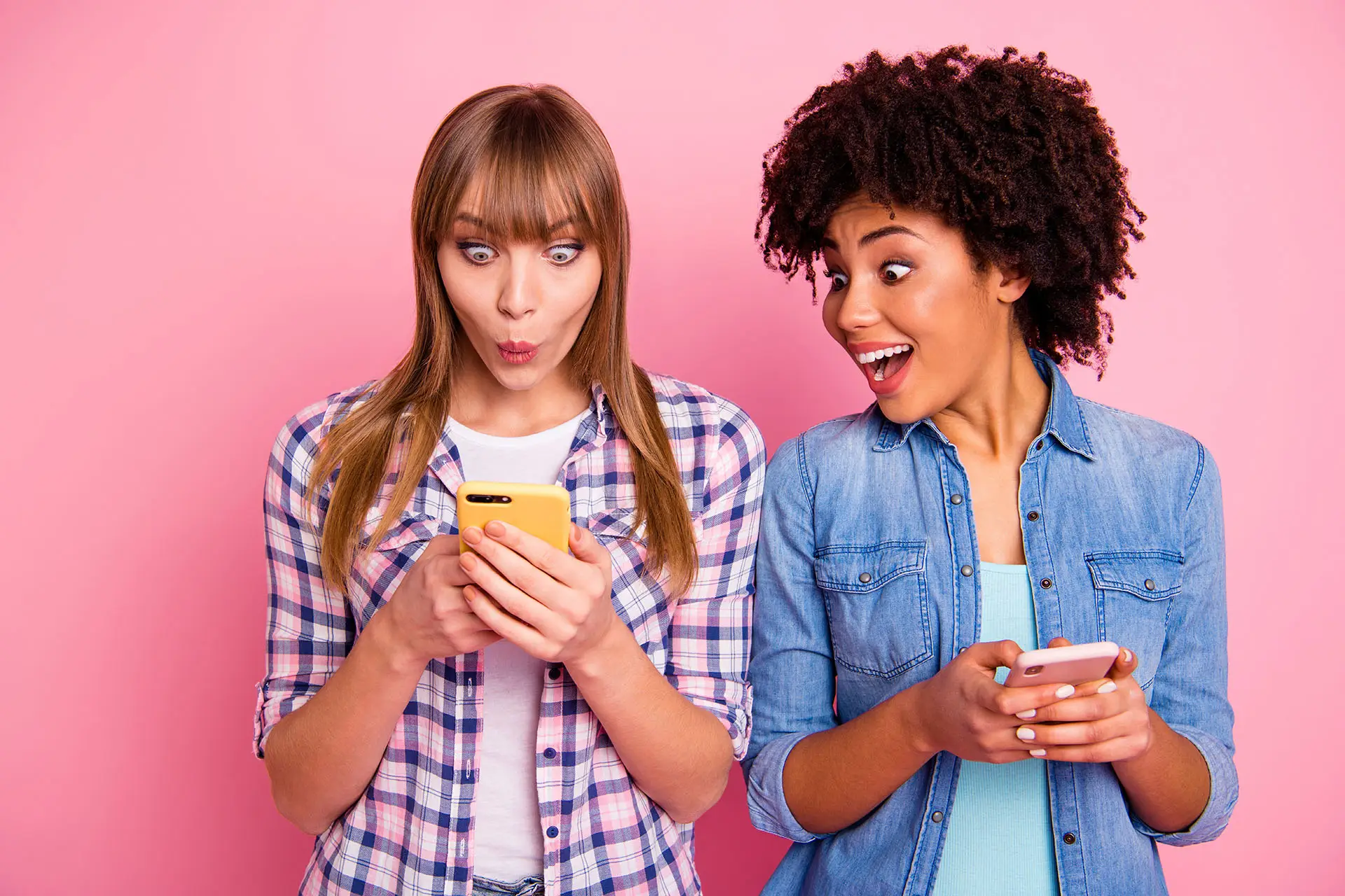 Social Media Engagement this image shows two ladies looking at their phone, one making a wow action with her mouth - engaging social media concept