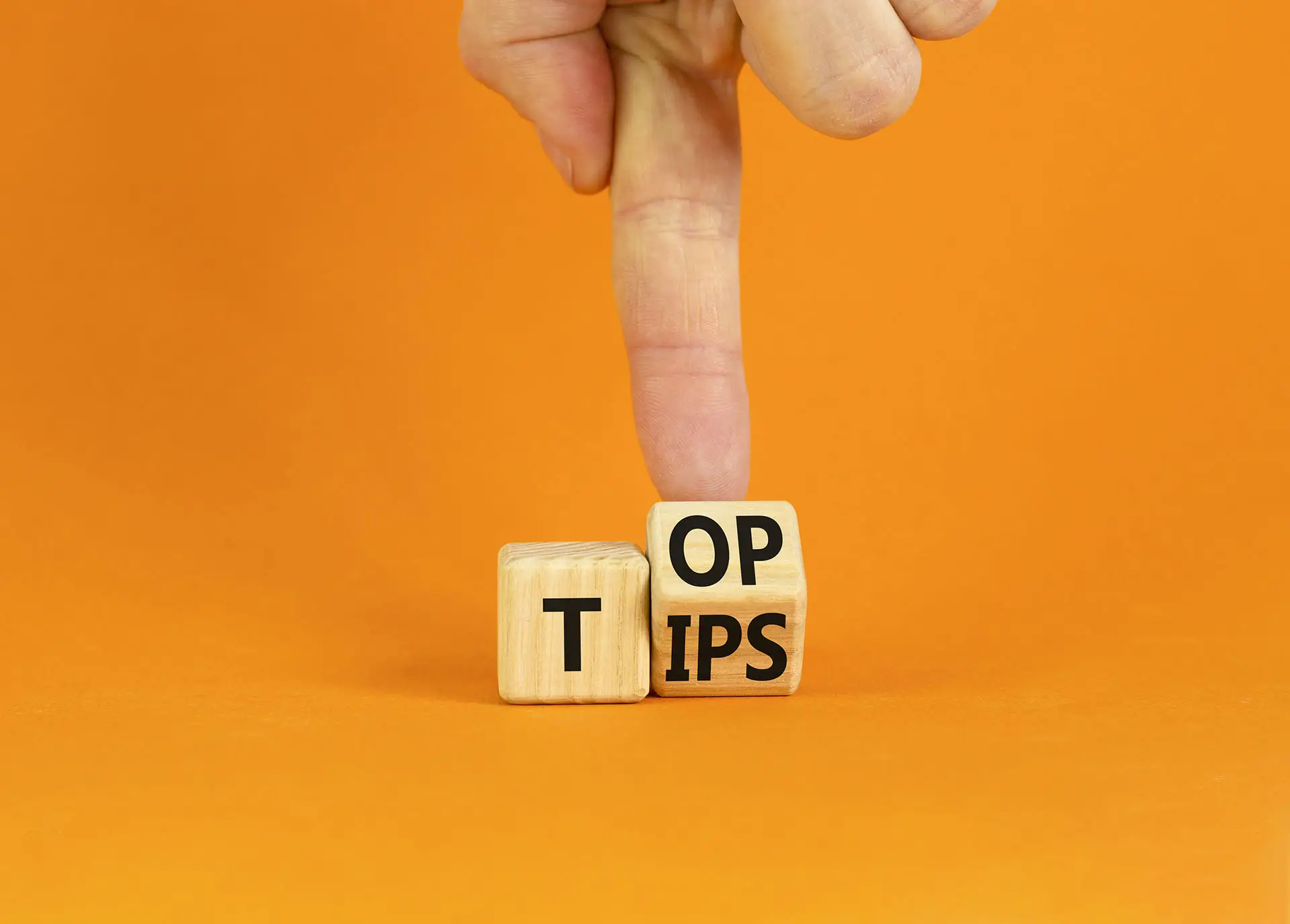 Social Media Marketing Tips the image shows an orange background with wooden blocks that have top and tips written on them and a hand flipping them over - social media tips concept