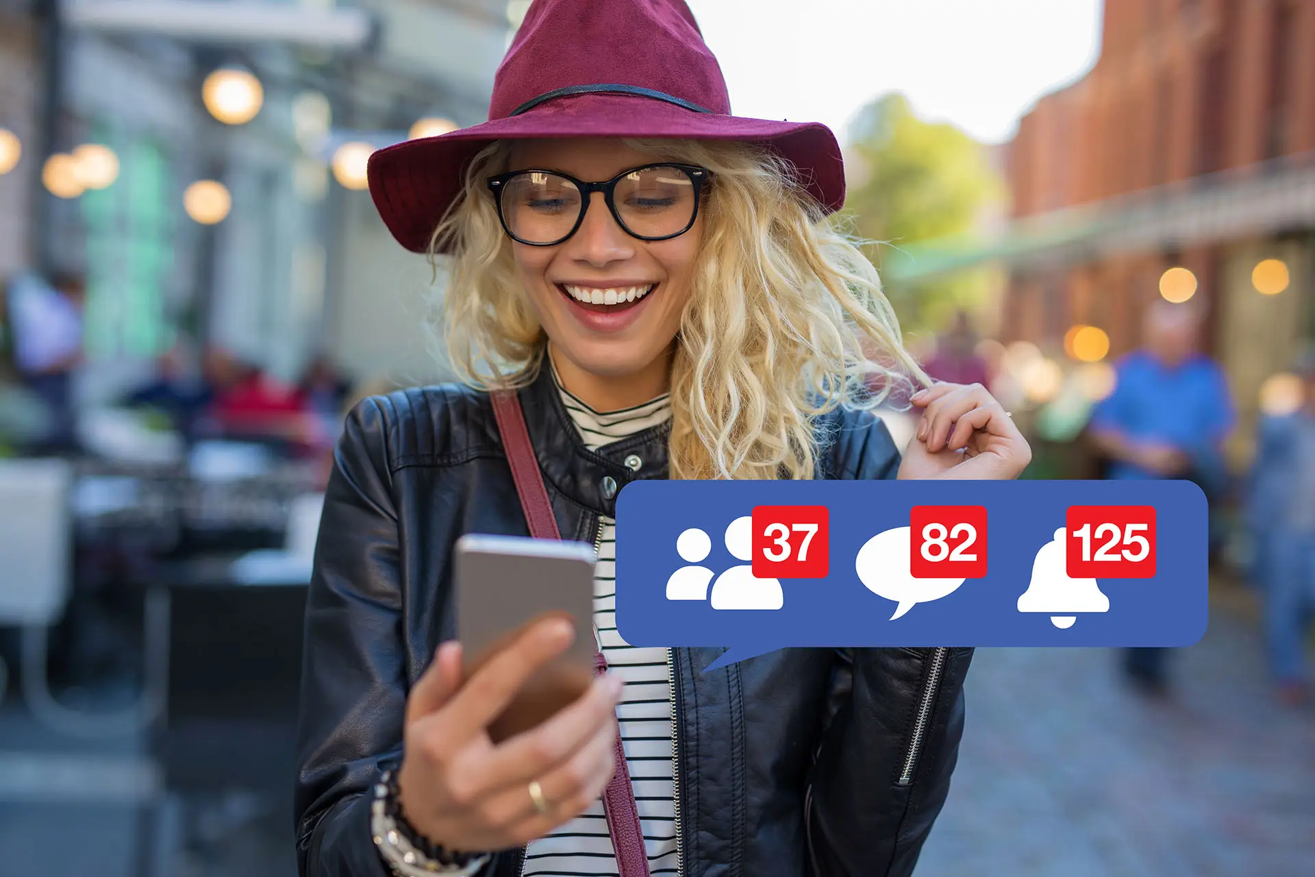 Social Media Numbers this image shows a happy lady on a town high street, she is wearing a plum coloured hat, glasses and is holding her phone in her hand, she is smiling at the content and social media notification icons are displayed with follows, comments and alerts - concept for social media numbers