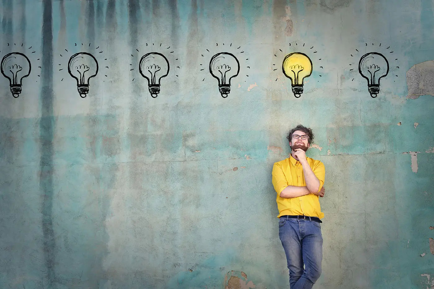 What to Blog About image shows a grey background with a thoughtful man stood under a row of lightbulbs that have been drawn onto the background, the lightbulb he stands under is lit.