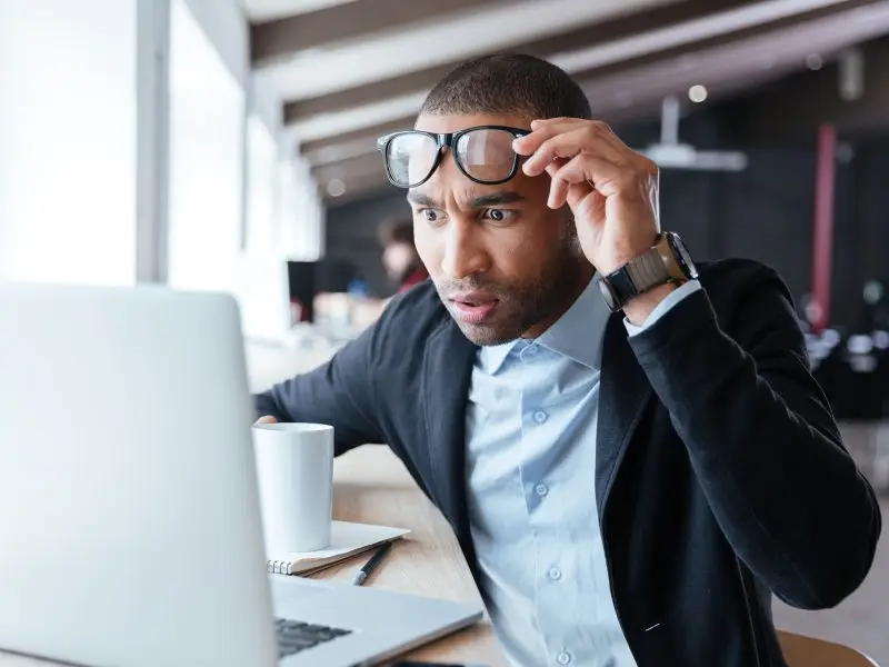 Why High Google Bounce Rates Can be Good. The image shows an attractive man looking at his laptop, he has raised his glasses and staring at the screen in disbelief