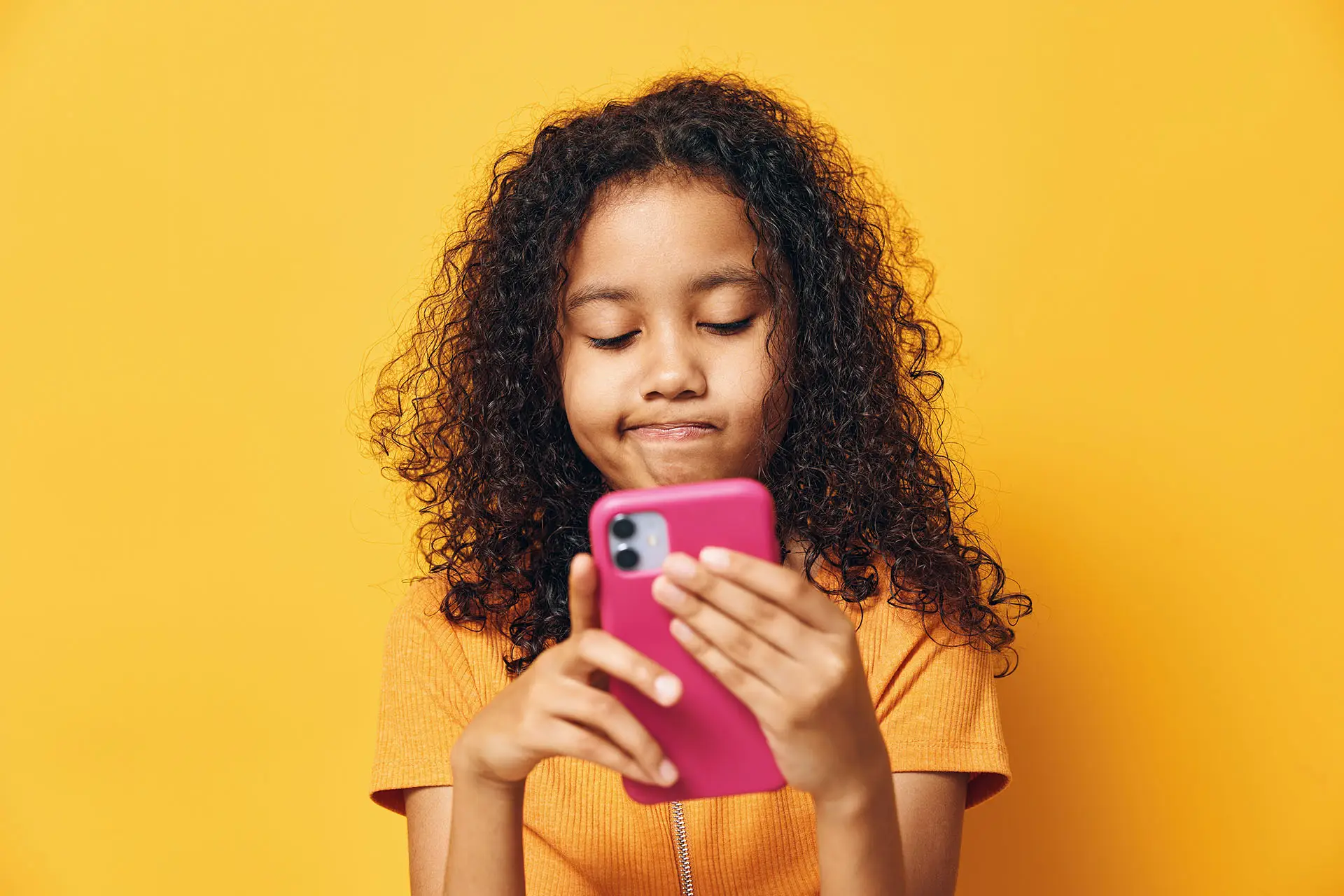 10 Tips for Keeping Children Safe on Social Media - this image shows a young girl on a mobile phone