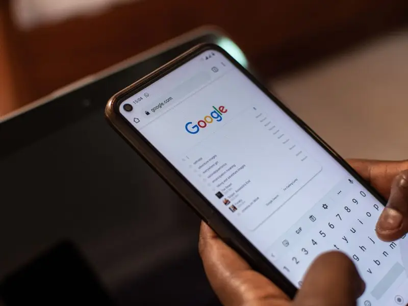 Changes Made to Google’s Webmaster Guidelines - this image shows a user holding a mobile phone starting a search on google