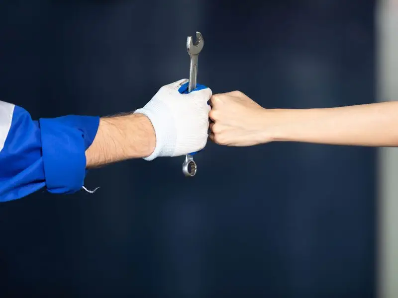 Effective Sales Techniques for Small Business Owners. This image shows two arms fist bumping, one is dressed in a mechanics overalls and the other is sleeveless - concept for small business sales