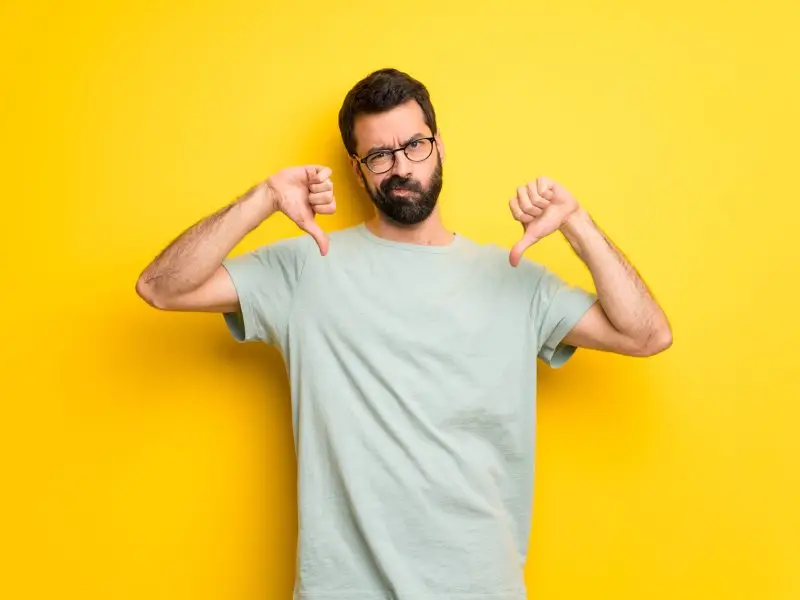 Facebook Dislike Button - this image shows a bright yellow background with a man in the foreground with both thumbs down