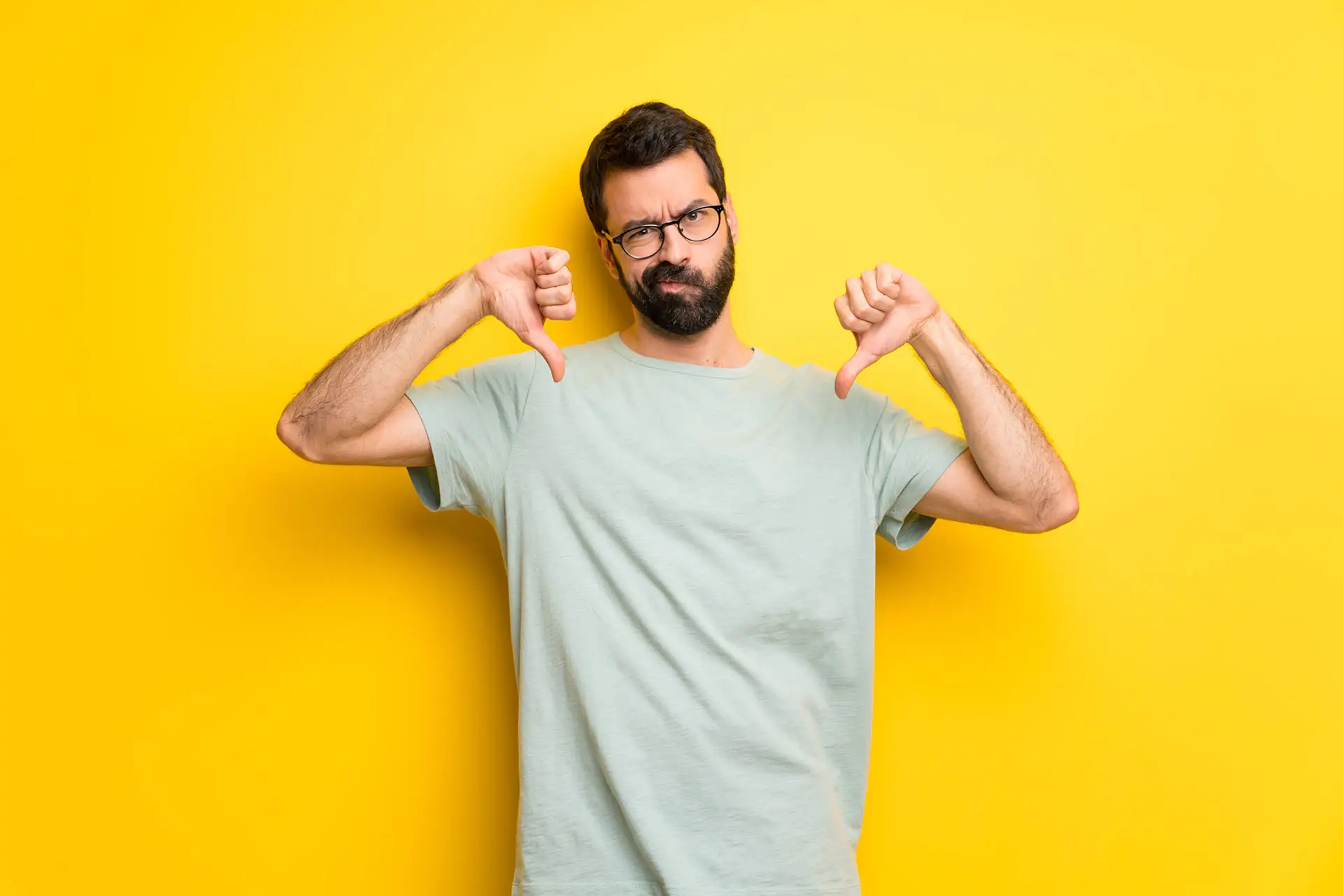 Facebook Dislike Button - this image shows a bright yellow background with a man in the foreground with both thumbs down