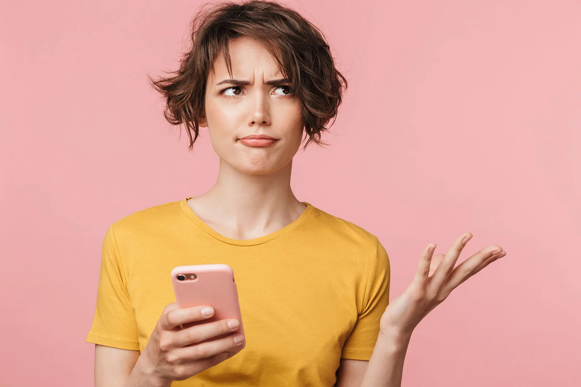 Google Algorithm Launch on 1st November - this image shows a pink background with a lady in a yellow top holding her mobile phone with her eyes rolled and her hand up questioningly