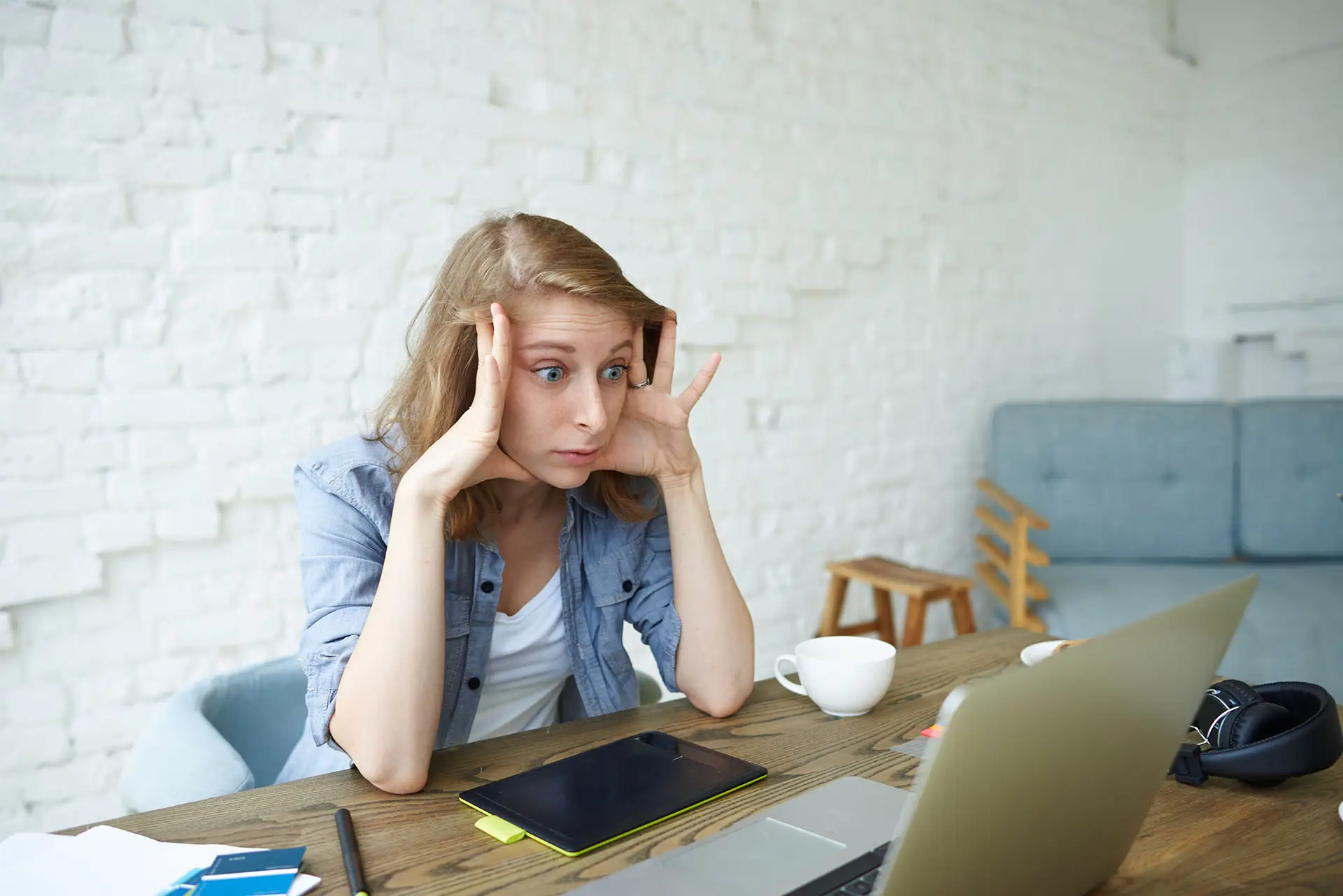 How To Write A 30 Minute Blog this image shows a lady sat at her laptop with her head propped up by her hands, a look of consternation on her face.