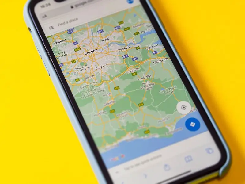 How to Add Google Maps to Your WordPress Website - this image shows a bright yellow background with a mobile phone displaying a Google map of the UK