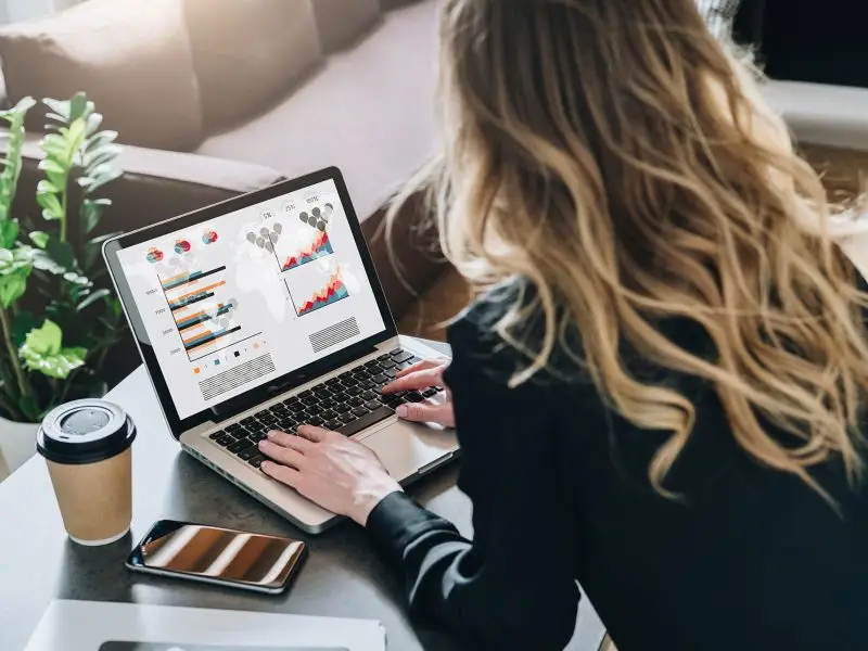 How to Open a Google Analytics Account - this image shows a lady with her back to the camera, work at her desk, on her laptop is various analytics data