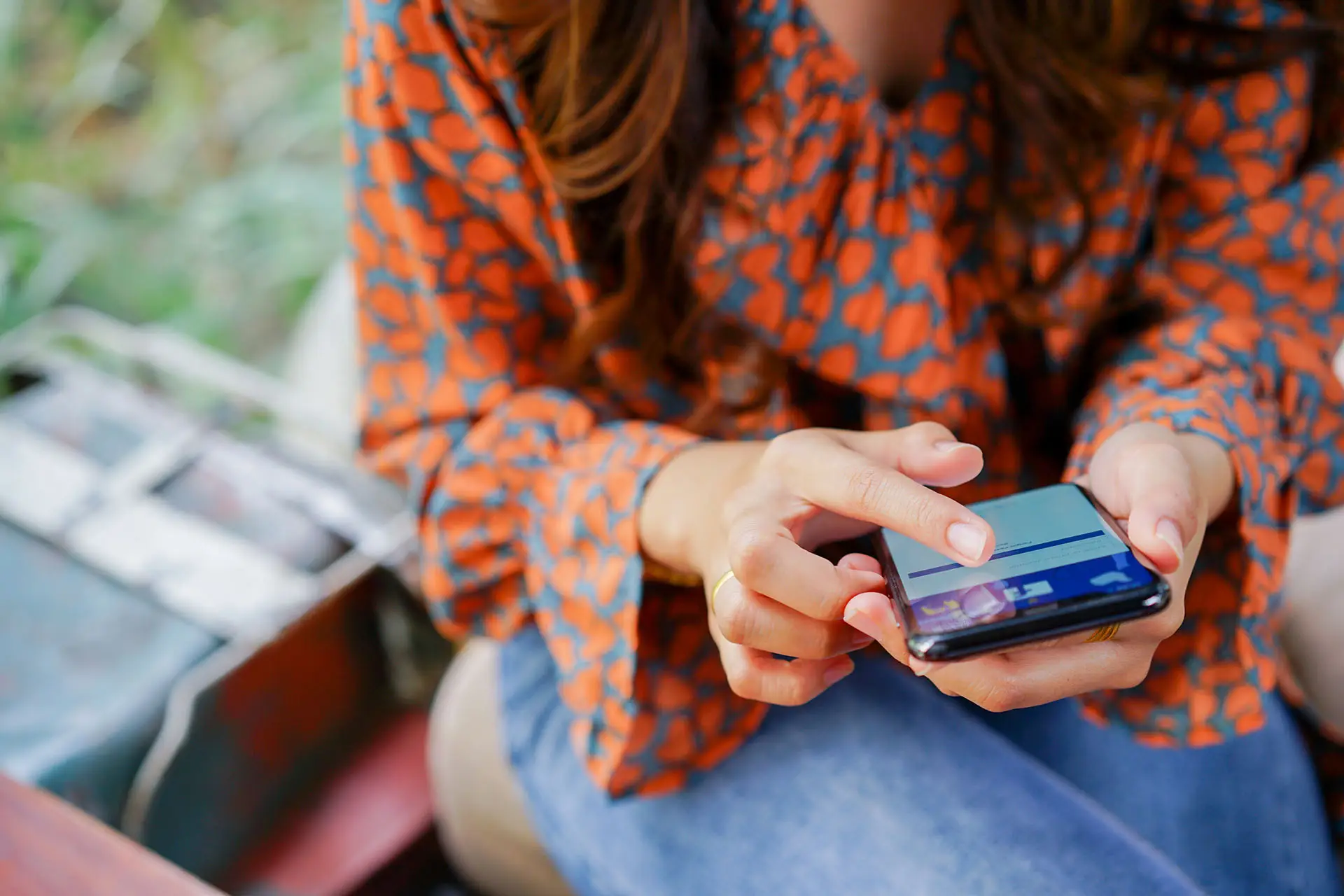 Adding a Services Section to Your Facebook Business Page - this image shows a lady in an orange and blue shirt using Facebook Business Pages on her phone