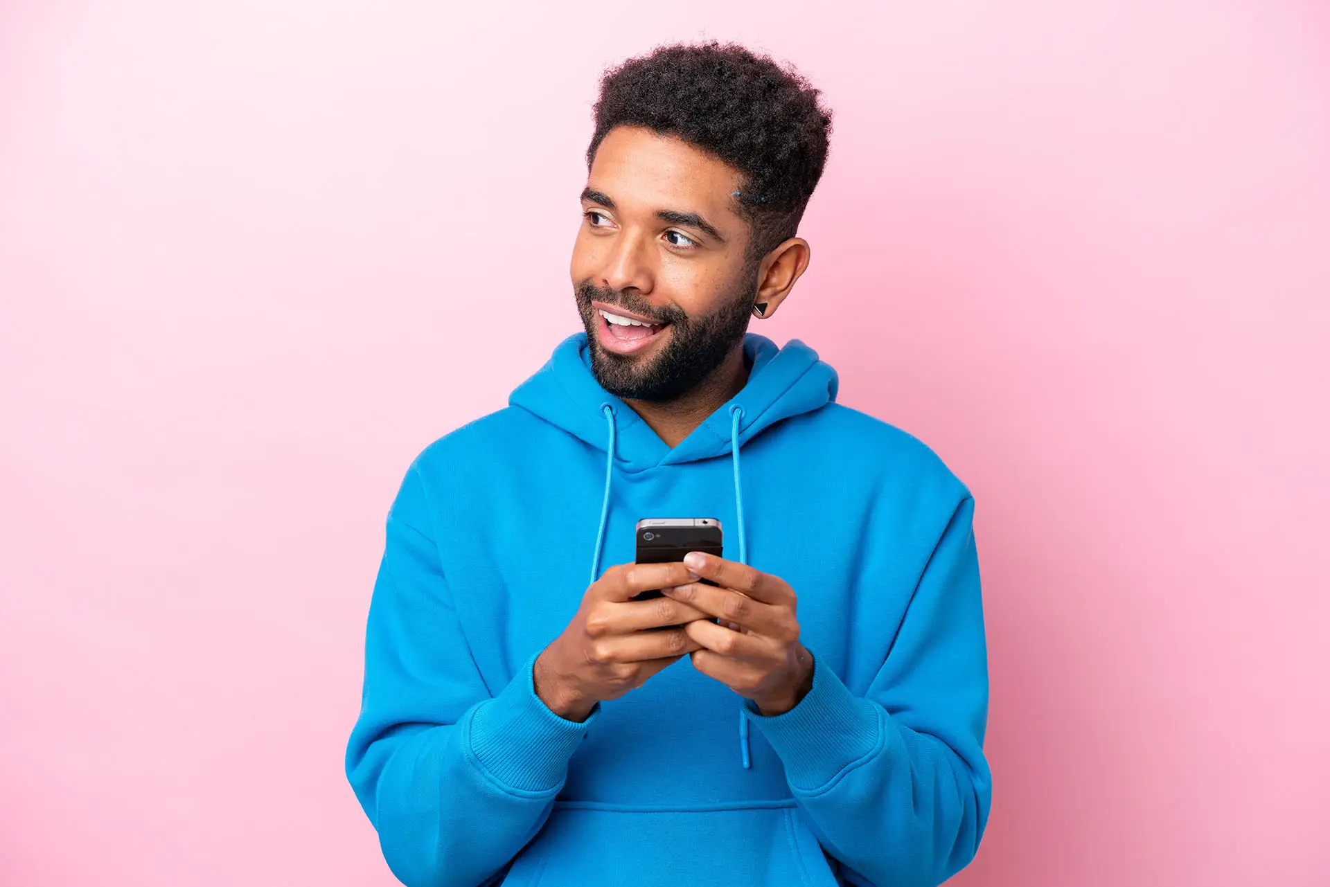 Facebook Messenger Ads this image shows a pink background with a man in a blue top smiling and looking up from the phone that is in his hands