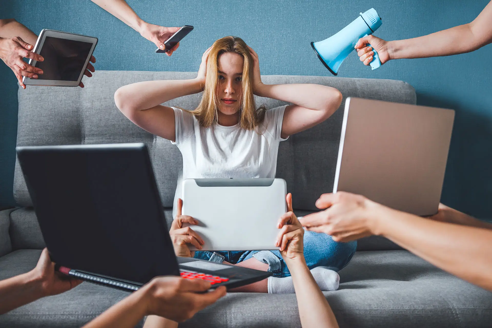 Is “Fake News” News? This image shows a young girl sat on a sofa with her hands over her ears and lots of hands holding various devices including a laptop mobile, tablets and a megaphone. Concept for a deluge of fake news