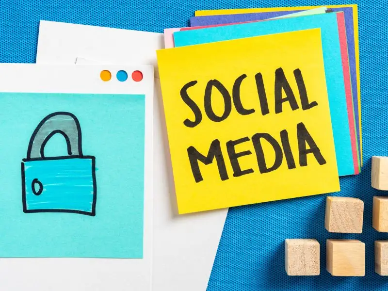 Keeping Your Social Media Accounts Secure - this image shows a bright blue background with a bright yellow note which says "social Med" and another blue one with a picture of a padlock - concept for securing social media accounts