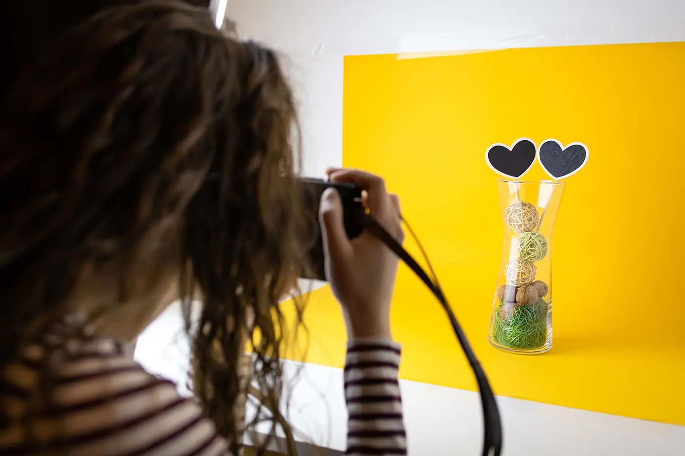 Product Photography Tips - this image shows a photographer taking pictures of a product set up, the background for the image is a plain bright yellow background - concept for using a plain background