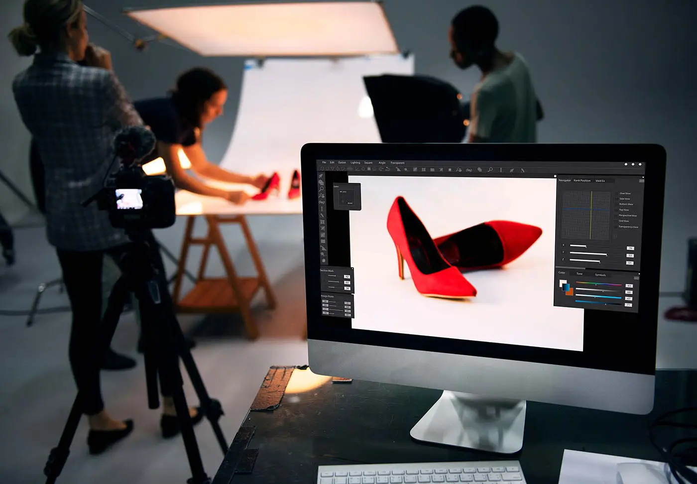 Product Photography Tips - this image shows a photography team setting up a product (red shoes) in a lighted area, the shot of the product is showing on a laptop in the foreground