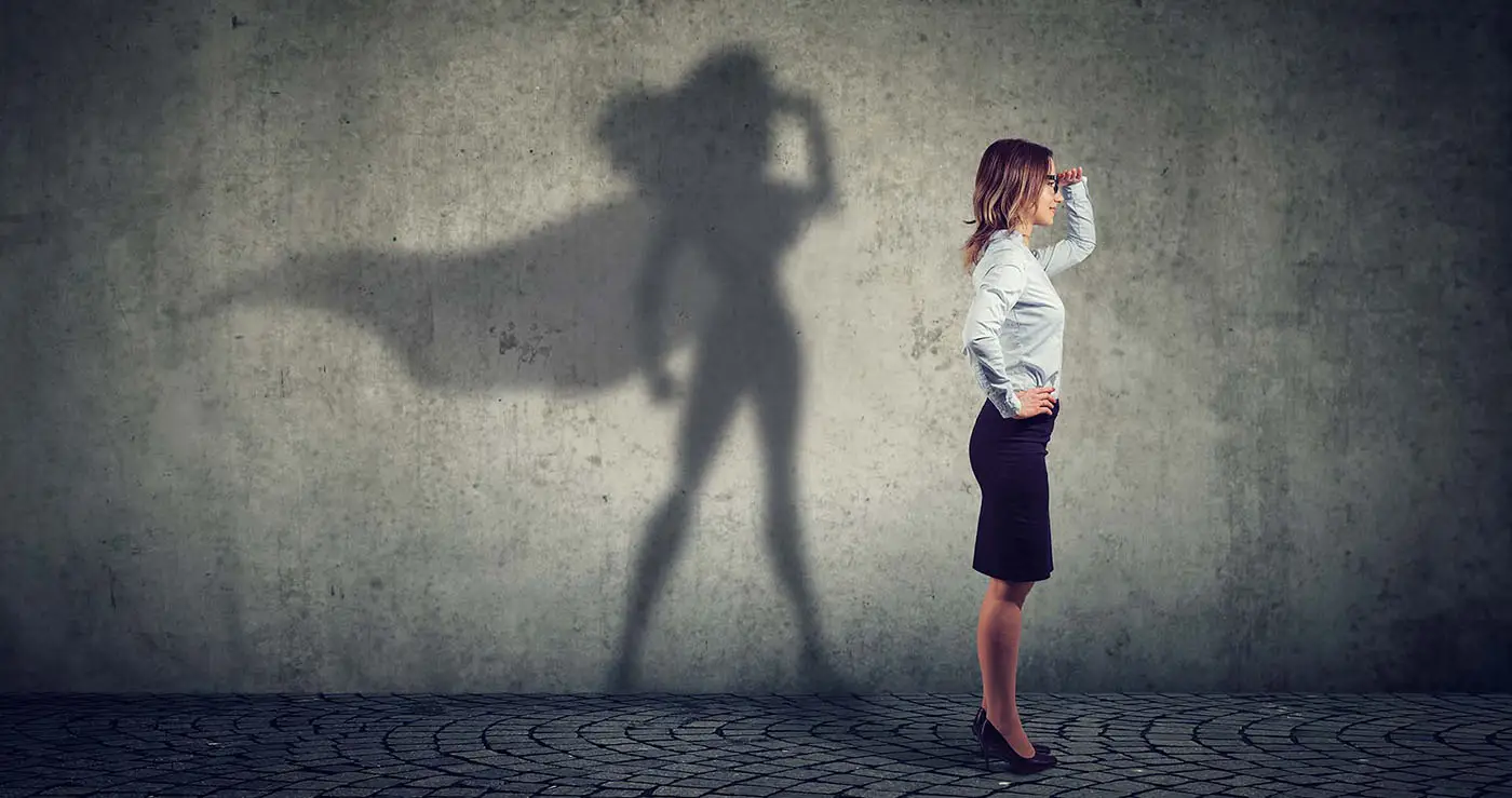 Protecting Your WordPress Website - this image shows a light grey back drop, there is a lady stood in the foreground dressed in business attire, her shadow shows her as a superhero - concept for managing website security