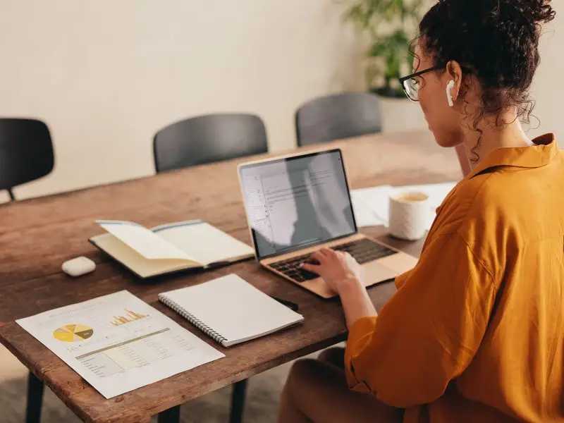 Tips for Working Productively from Home - this image shows a lady in bright yellow shirt, working at her kitchen table