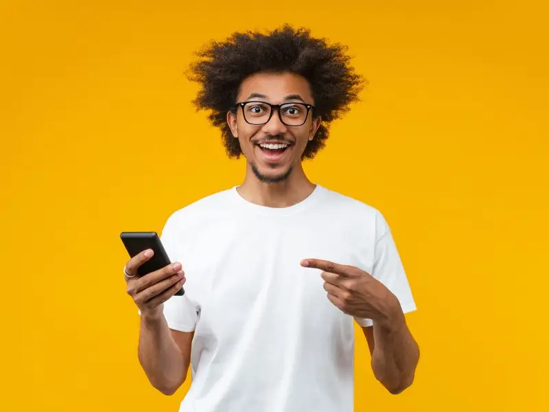 Twitter Increases to 280 Characters - this image shows a bright yellow background with an excited man holding his phone and pointing at it - concept for the increased character length on twitter