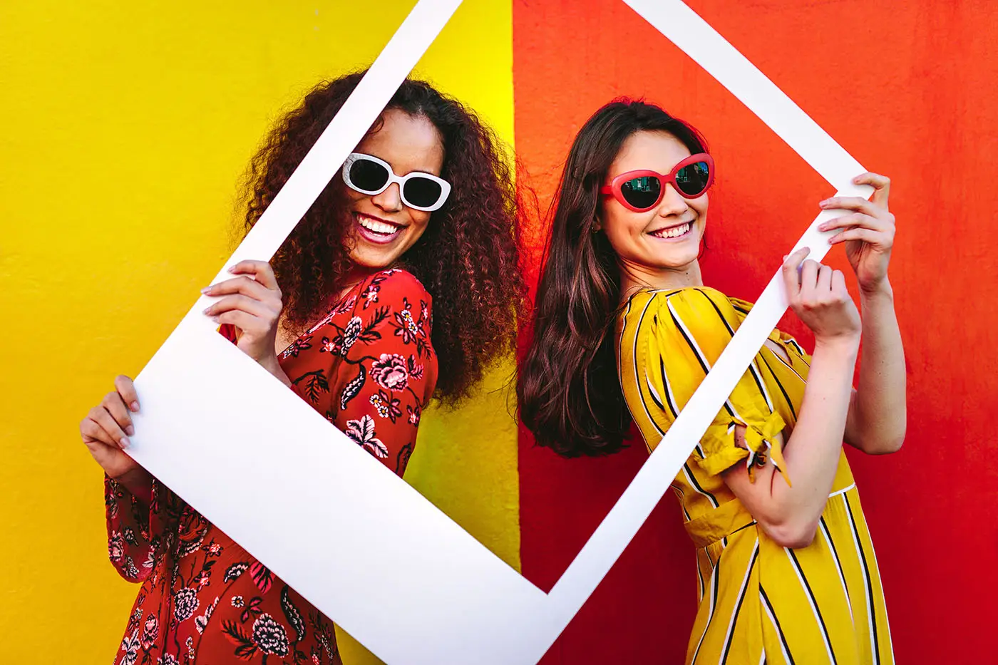 UK Social Media Statistics for 2019 - this image shows two ladies, one wearing red and the other yellow with opposite coloured backgrounds, they are sharing a selfies Instagram frame and are smiling