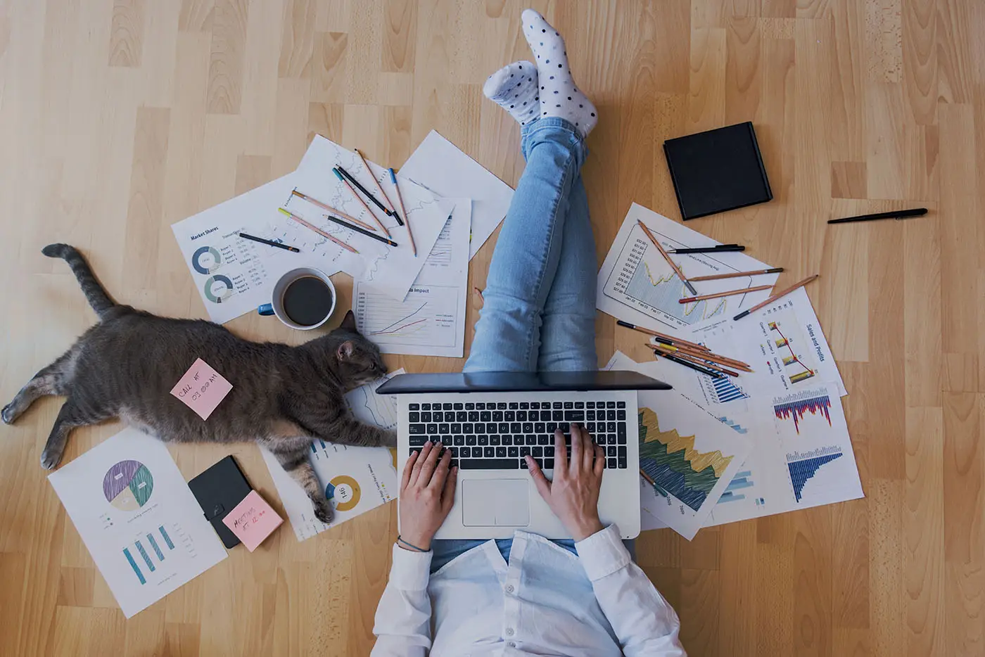 Understanding Where Your Website Truly Ranks - this image shows a person sat on a wooden floor with their laptop on their lap and various sheets of analytical data spread across the floor