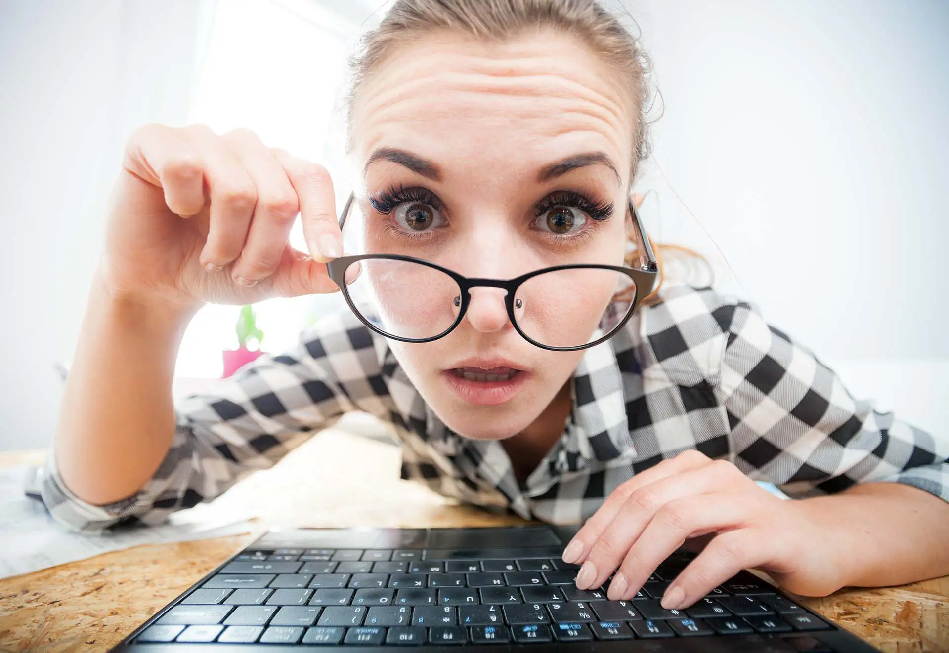 What To Include In A Blog Article - this image shows a young lady wearing glasses, peering into her laptop screen