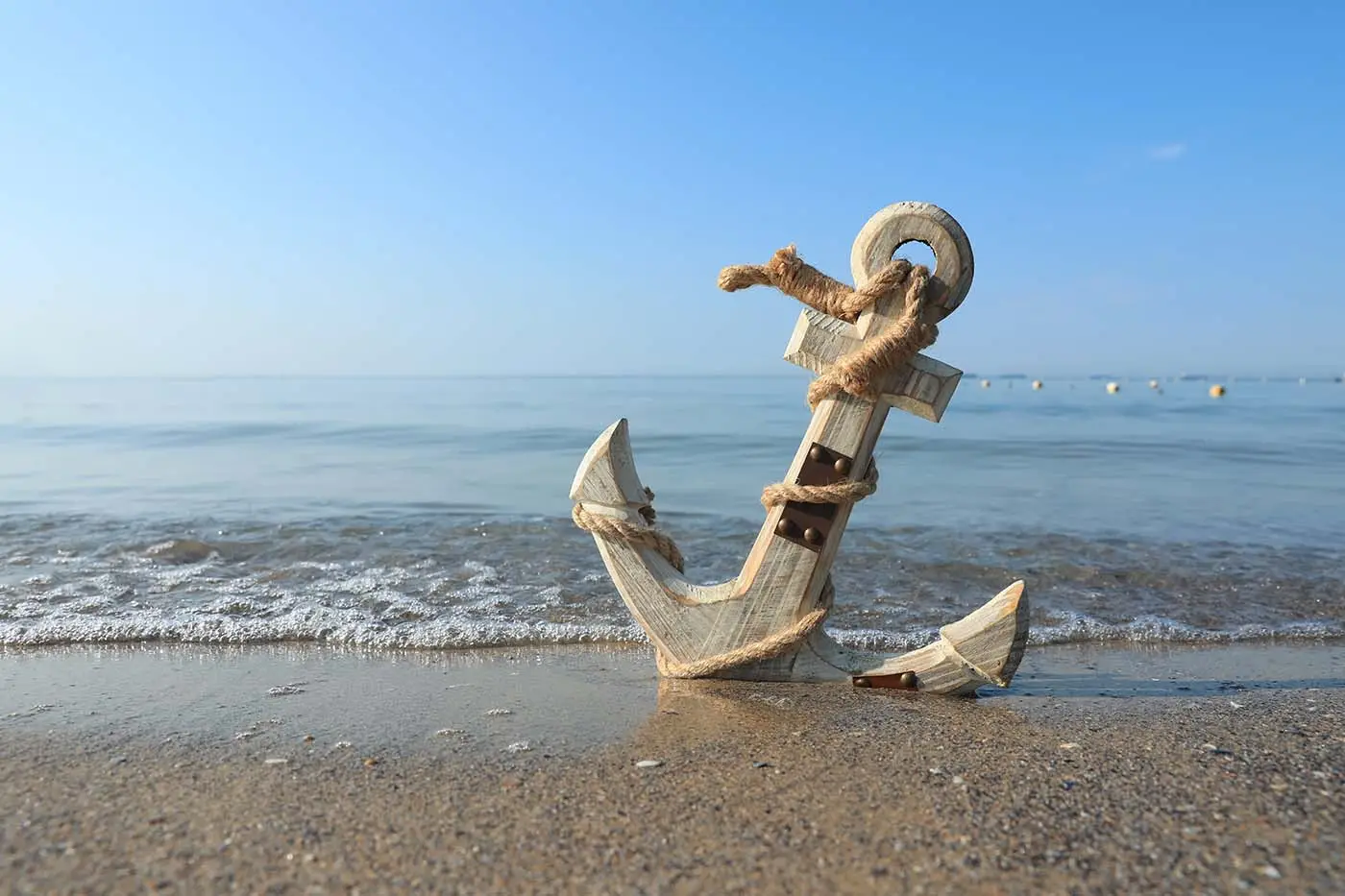 What is Anchor Text? This image shows a white wooden anchor sitting on a beach with the waves coming in