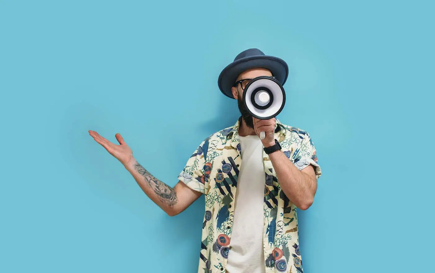 Why Giving Clients What They Want Isn't Always the Best Strategy - this image shows a light blue background with a man dressed in an floral shirt and a hat with a megaphone up to his face - communication concept