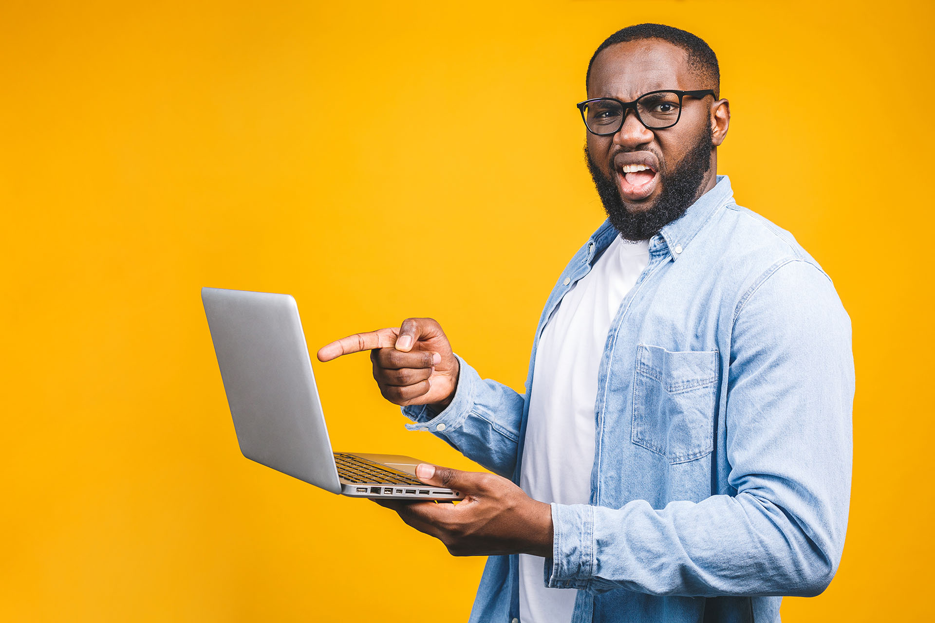 How to Clear Your Browser Cache - thuis image shows a bright yellow background with a man in glassess pointing at his laptop screen looking frustrated